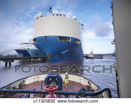 Worker standing on deck of tugboat View Large Photo Image Stock Image - Worker standing on deck of tugboat. Fotosearch