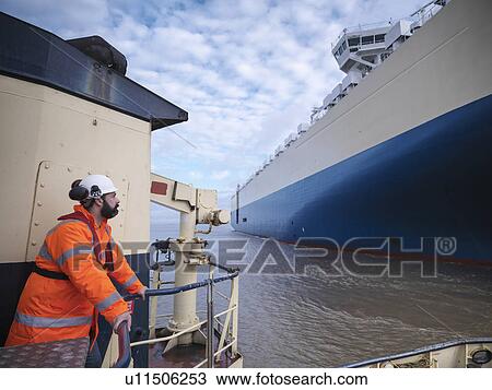 Worker standing on deck of tugboat View Large Photo Image Stock Image - Worker standing on deck of tugboat. Fotosearch