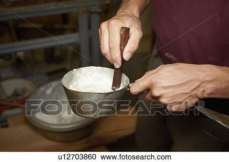 Stock Image - Worker stirring pot in shop. Fotosearch