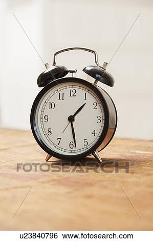 Alarm clock on wooden table View Large Photo Image Stock Photograph - Alarm clock on wooden table. Fotosearch