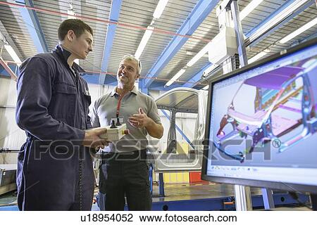 Stock Image - Apprentice learning in car factory. Fotosearch