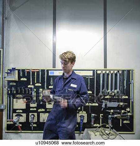 Apprentice standing in car factory View Large Photo Image Stock Photo - Apprentice standing in car factory. Fotosearch