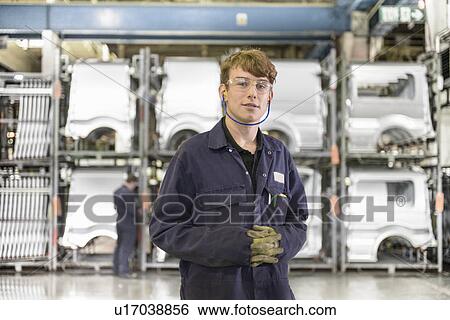 Stock Photograph - Apprentice standing in car factory. Fotosearch