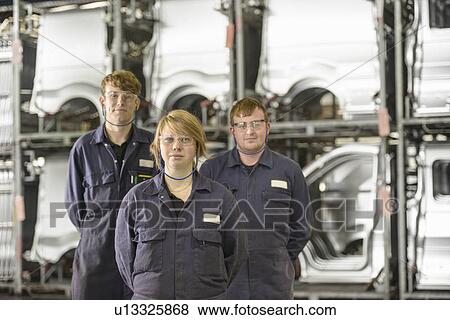 Stock Photo - Apprentices standing in car factory. Fotosearch