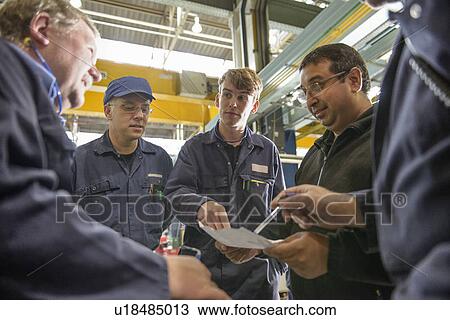 Stock Image - Apprentices talking in factory. Fotosearch