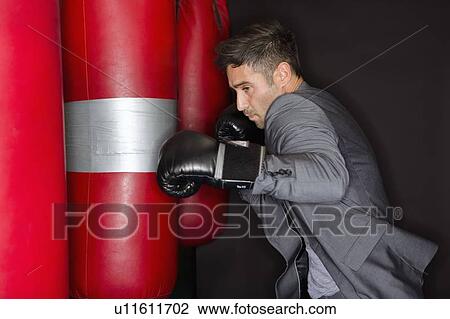 Stock Image - Boxer training with punching bag. Fotosearch
