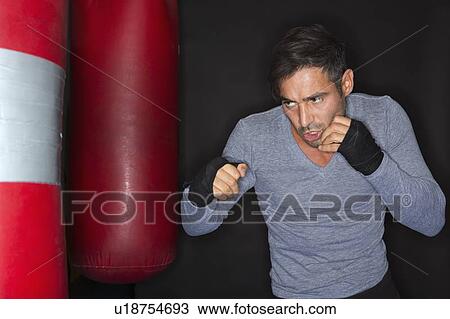 Stock Image - Boxer training with punching bag. Fotosearch