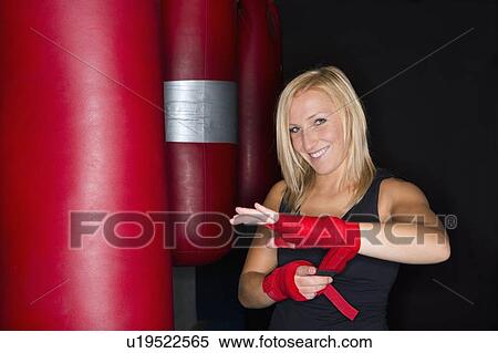 Stock Photography - Boxer wrapping her hands in gym. Fotosearch