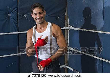Stock Image - Boxer wrapping his wrists in ring. Fotosearch