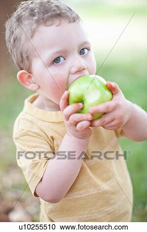 Stock Image - Boy eating apple outdoors. Fotosearch