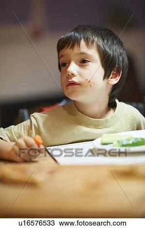 Stock Image - Boy eating at table. Fotosearch