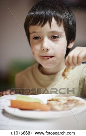 Boy eating at table View Large Photo Image Stock Photo - Boy eating at table. Fotosearch