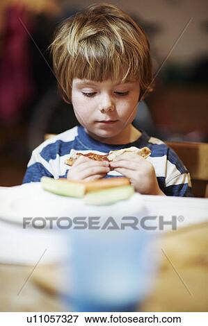Boy eating at table View Large Photo Image Stock Photo - Boy eating at table. Fotosearch