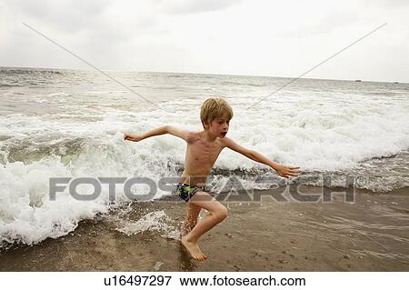 Boy playing in waves on beach View Large Photo Image Stock Photo - Boy playing in waves on beach. Fotosearch