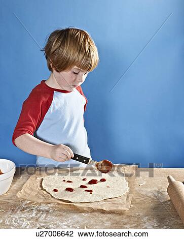 Boy spreading sauce on pizza dough View Large Photo Image Stock Image - Boy spreading sauce on pizza dough. Fotosearch