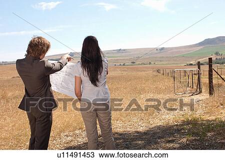 Stock Image - Business people reading blueprints. Fotosearch