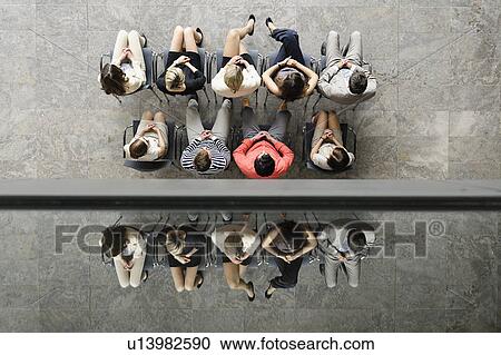 Stock Image - Business people sitting in waiting area. Fotosearch