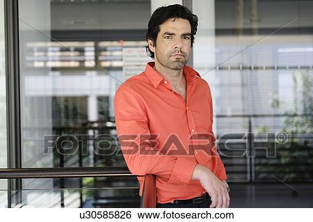 Businessman leaning on railing in office View Large Photo Image Stock Photograph - Businessman leaning on railing in office. Fotosearch