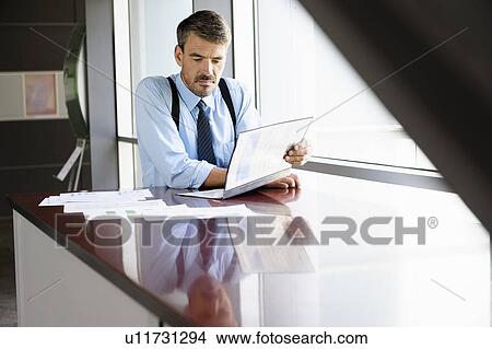 Businessman reading at desk View Large Photo Image Picture - Businessman reading at desk. Fotosearch