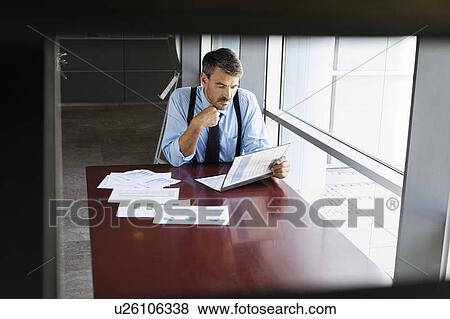 Businessman reading at desk View Large Photo Image Stock Photo - Businessman reading at desk. Fotosearch