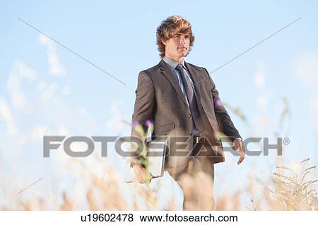Stock Photo - Businessman with laptop in tall grass. Fotosearch