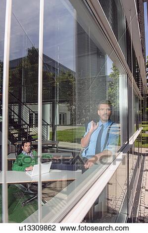 Stock Image - Businessmen in office behind window. Fotosearch