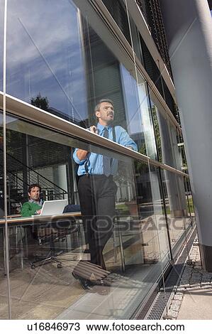 Stock Image - Businessmen in office behind window. Fotosearch