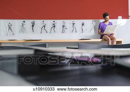 Stock Image - Businesswoman reading in office. Fotosearch