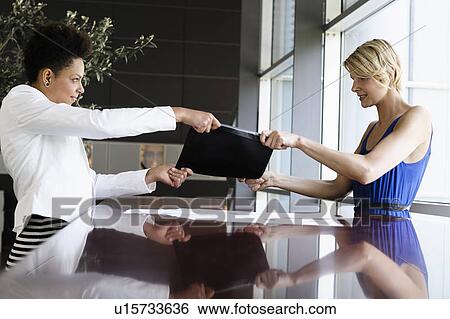 Stock Photograph - Businesswomen fighting over folder. Fotosearch