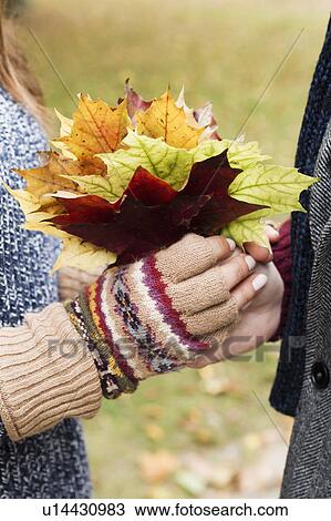 Stock Image - Close up of couple holding autumn leaves. Fotosearch