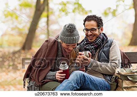 Couple drinking coffee on park bench View Large Photo Image Stock Image - Couple drinking coffee on park bench. Fotosearch