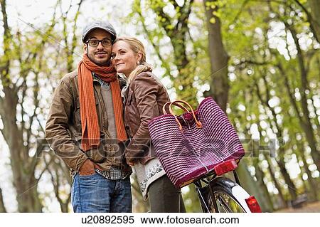 Stock Photography - Couple hugging by bicycle in forest. Fotosearch