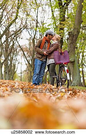 Couple kissing by bicycle in forest View Large Photo Image Stock Image - Couple kissing by bicycle in forest. Fotosearch