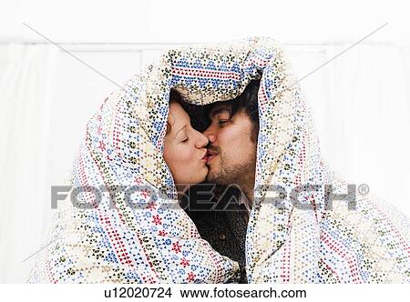 Picture - Couple kissing under duvet blanket. Fotosearch