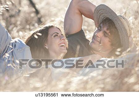 Stock Image - Couple laying in tall grass. Fotosearch