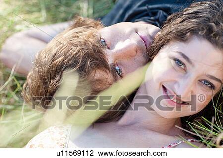 Stock Image - Couple laying together in tall grass. Fotosearch