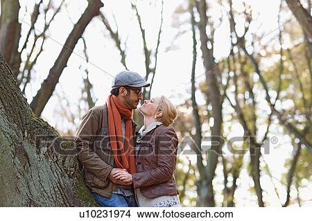 Picture - Couple leaning against tree in forest. Fotosearch