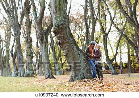 Couple leaning against tree in forest View Large Photo Image Stock Image - Couple leaning against tree in forest. Fotosearch