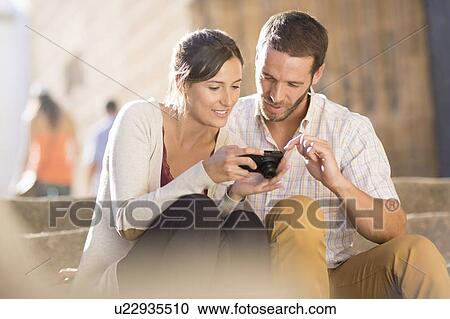 Couple looking at pictures on camera View Large Photo Image Stock Image - Couple looking at pictures on camera. Fotosearch