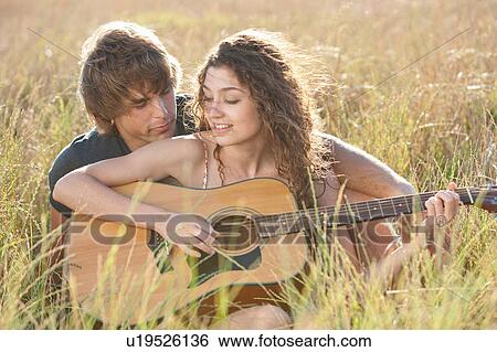 Couple playing guitar in tall grass View Large Photo Image Stock Photograph - Couple playing guitar in tall grass. Fotosearch