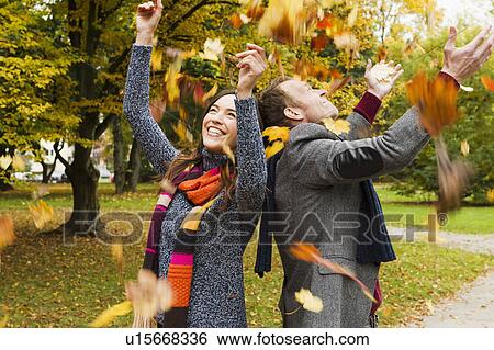Couple playing in autumn leaves View Large Photo Image Stock Photograph - Couple playing in autumn leaves. Fotosearch