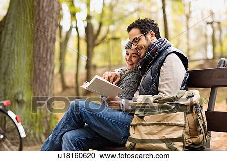 Couple reading together on park bench View Large Photo Image Stock Image - Couple reading together on park bench. Fotosearch