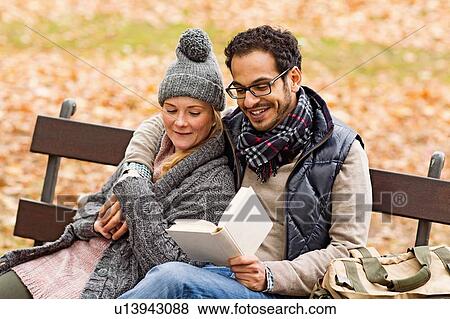Couple reading together on park bench View Large Photo Image Stock Photo - Couple reading together on park bench. Fotosearch