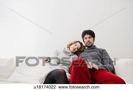 Stock Image - Couple relaxing on sofa together. Fotosearch