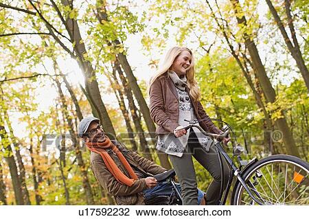 Couple riding bicycle in forest View Large Photo Image Stock Image - Couple riding bicycle in forest. Fotosearch
