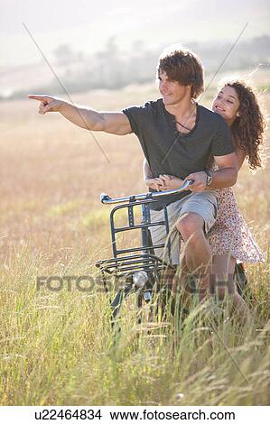 Couple riding bicycle in tall grass View Large Photo Image Picture - Couple riding bicycle in tall grass. Fotosearch