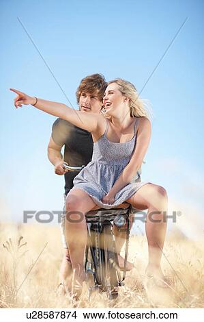 Picture - Couple riding bicycle in tall grass. Fotosearch