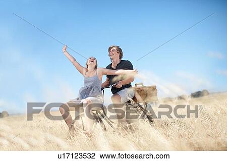 Couple riding bicycle in tall grass View Large Photo Image Stock Image - Couple riding bicycle in tall grass. Fotosearch