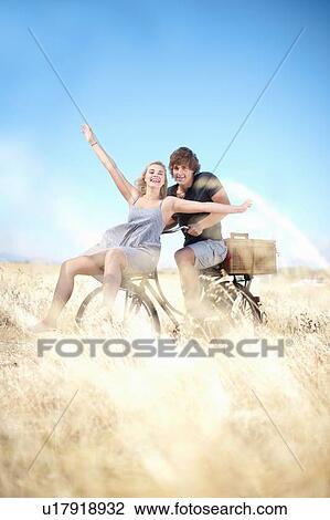 Couple riding bicycle in tall grass View Large Photo Image Stock Image - Couple riding bicycle in tall grass. Fotosearch