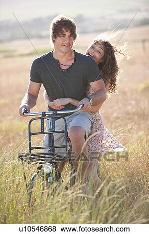 Couple riding bicycle in tall grass View Large Photo Image Stock Photo - Couple riding bicycle in tall grass. Fotosearch